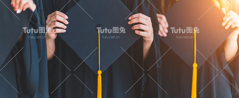 特写一群在大学毕业典礼上拿着帽子的毕业生