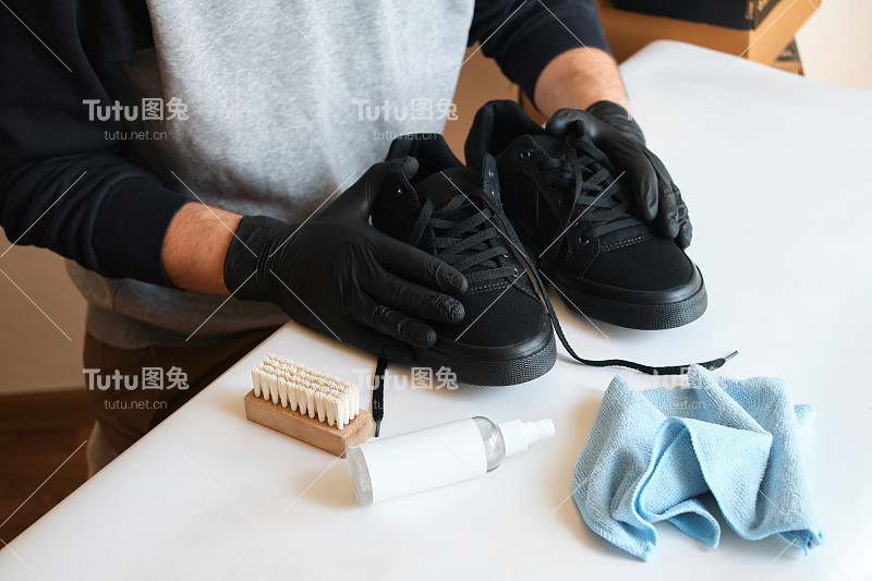 一个男人正在车间里清洗运动鞋。擦鞋服务服务。鞋匠准备应季的鞋子。鞋刷特写。鞋子护理用一种特殊的产品