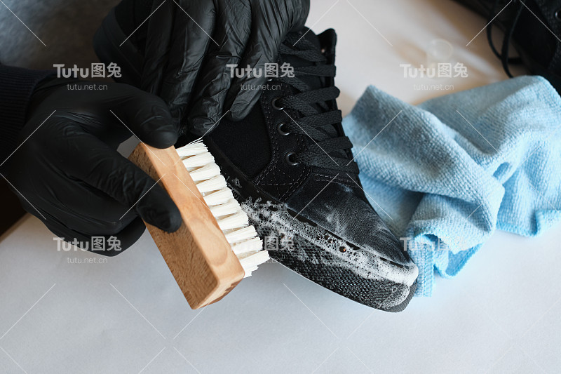 一个男人正在车间里清洗运动鞋。擦鞋服务服务。鞋匠准备应季的鞋子。鞋刷特写。鞋子护理用一种特殊的产品