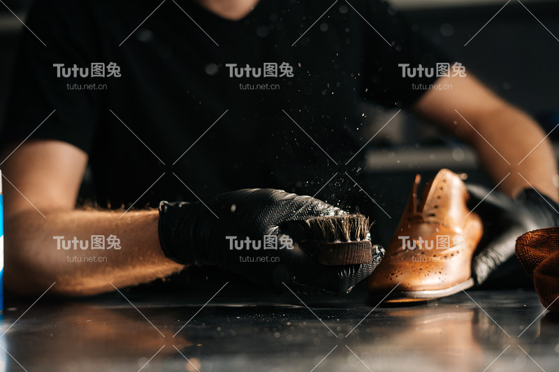 特写的男人在黑色乳胶手套清洁鞋刷，刷灰尘和污垢与手指。