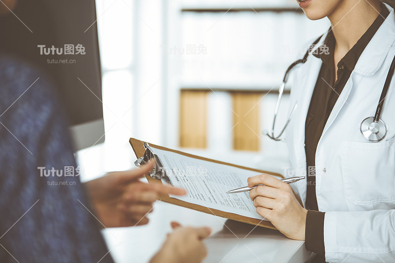 医生和病人坐在诊所讨论当前的健康检查。医院完善的医疗服务