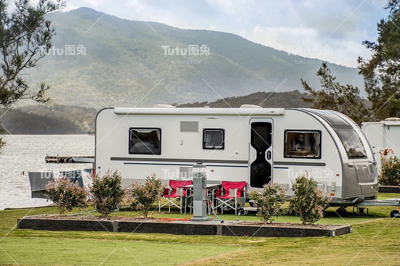 房车露营车露营在湖边的房车公园，地平线上有山。露营度假旅游概念