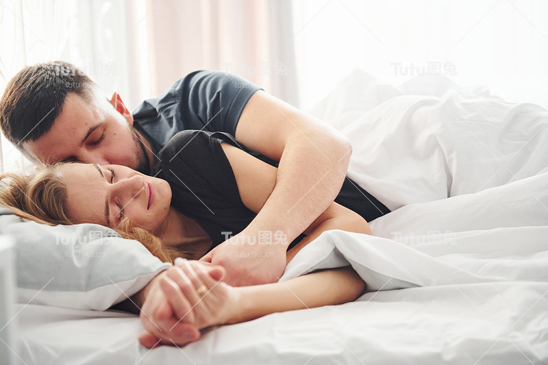 可爱的年轻夫妇躺在床上，睡在一起