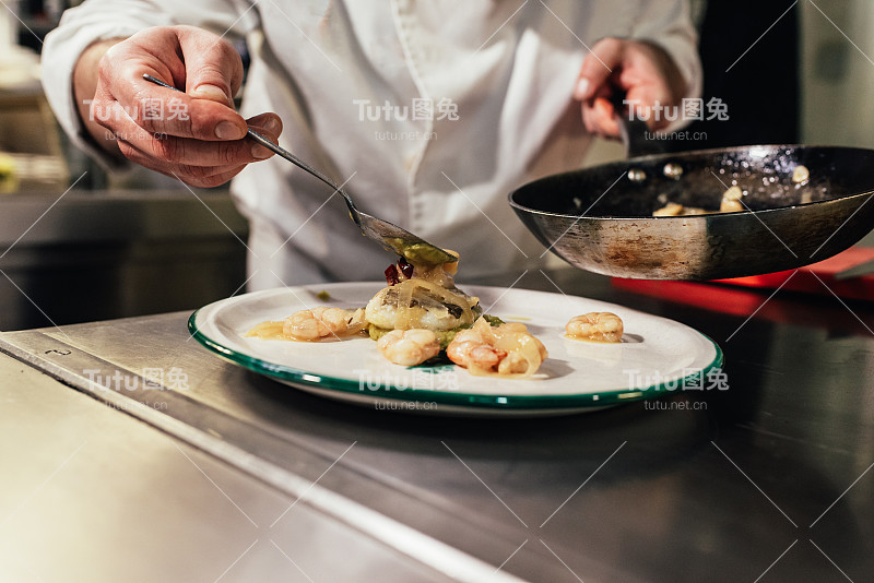 在餐厅厨房工作的男厨师正在做一道美食。