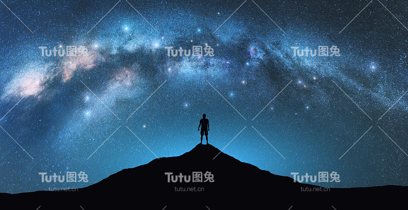 星夜银河拱，峰上人。一个人的剪影，夏日的蓝天，明亮的星星。星系。空间背景。拱形的银河景观。旅游和自然
