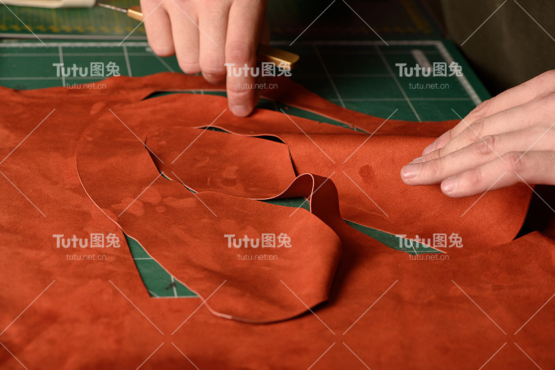 鞋匠的手握工艺刀切割绒面革的手工鞋在他的工作场所的车间。特写镜头。有选择性的重点。