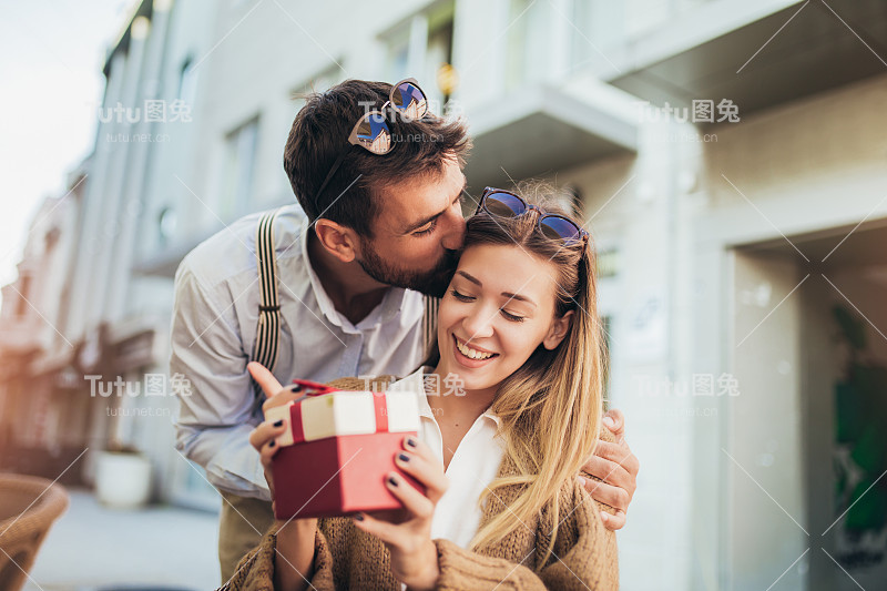 在咖啡馆里，一个年轻人给一个年轻女孩送了一份礼物