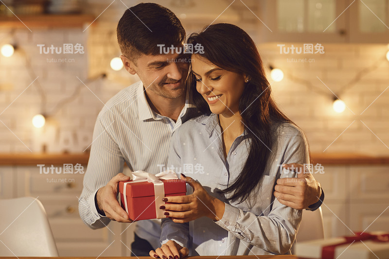 情人节那天，恋爱中的小伙子温柔地拥抱他的女朋友，并送给她一份情人节礼物。