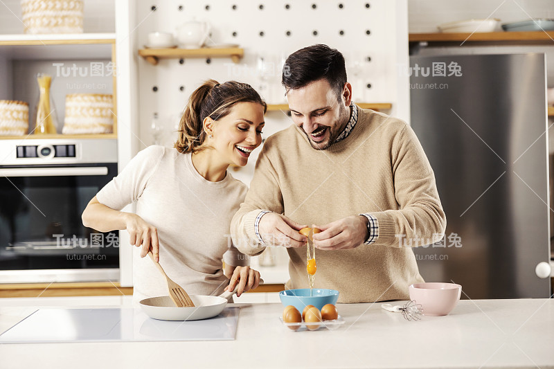 一对幸福的夫妇在他们舒适的公寓里准备早餐鸡蛋。