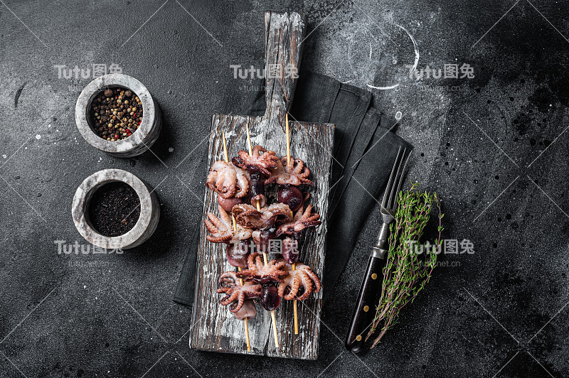 烤小章鱼串。黑色背景。俯视图