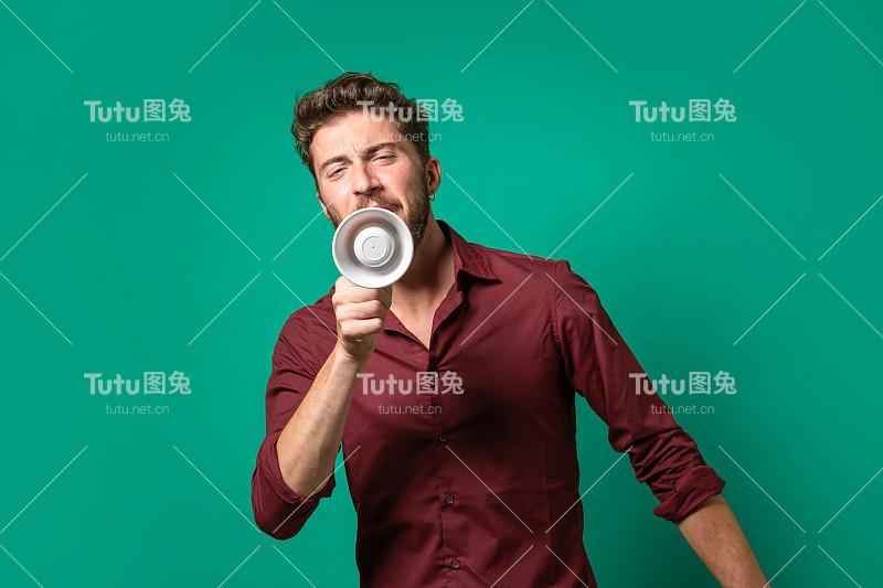 一个穿着石榴红衬衫的年轻人用扩音器呼喊