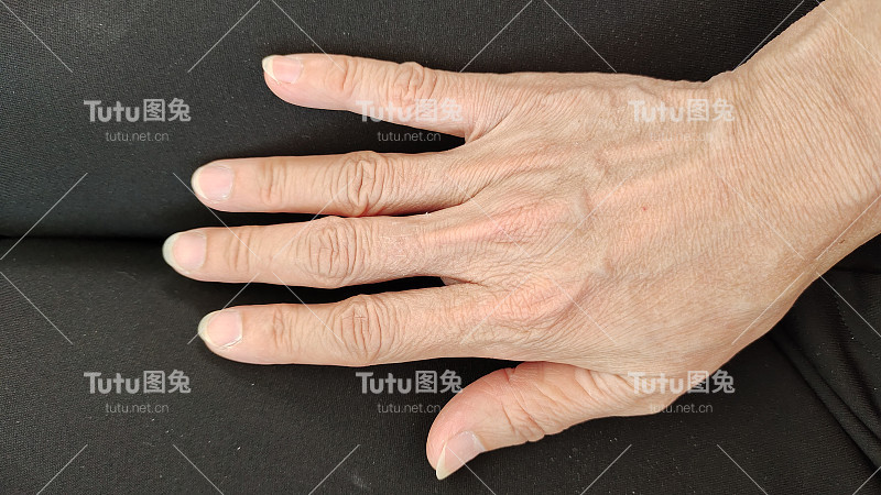 女性的手在黑色的背景上有皱纹。