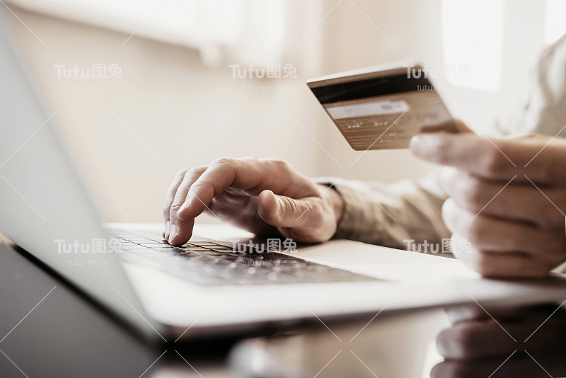 在线支付。年轻人在家用信用卡使用笔记本电脑