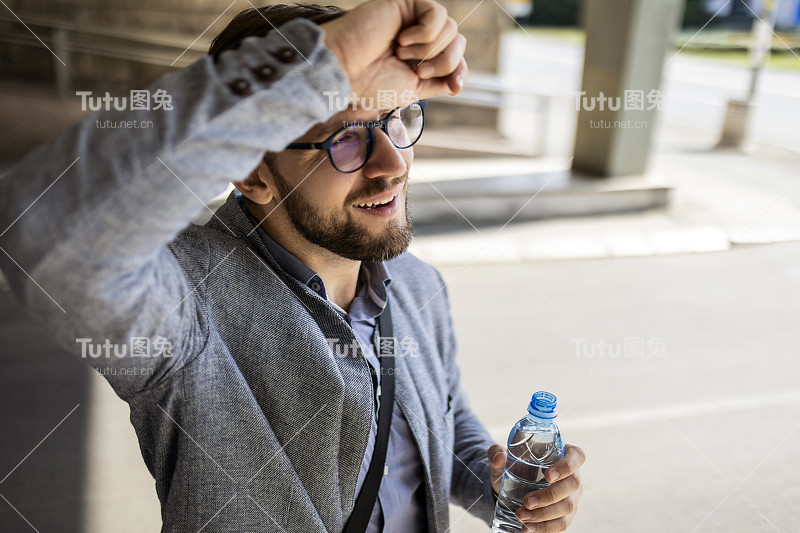 商人拿着水瓶喝水擦汗