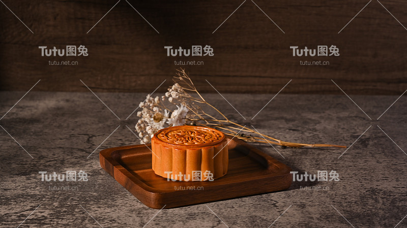 传统的中国月饼与茶和装饰与干花在质朴的石头背景。
