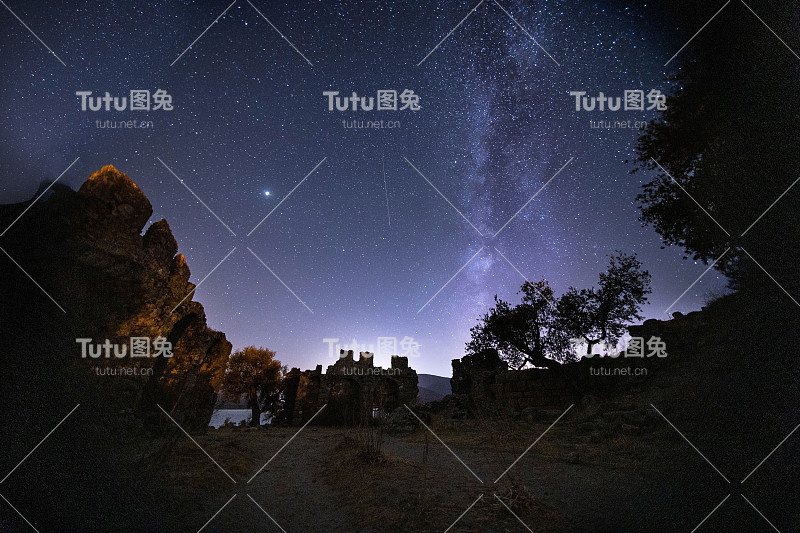 城堡的夜景。在前景中有一座山顶的银河系的星星的视图。夜空自然夏景。英仙座流星雨观测