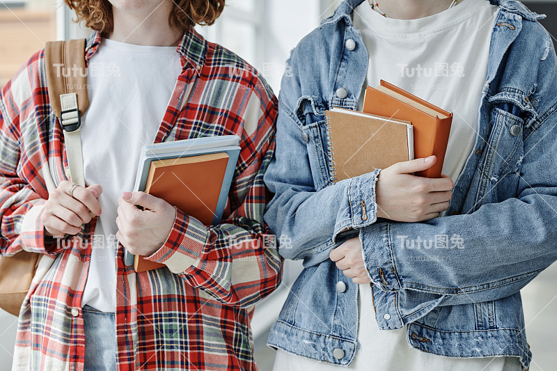 特写的两个友好的十几岁的女孩在休闲服装拿着书