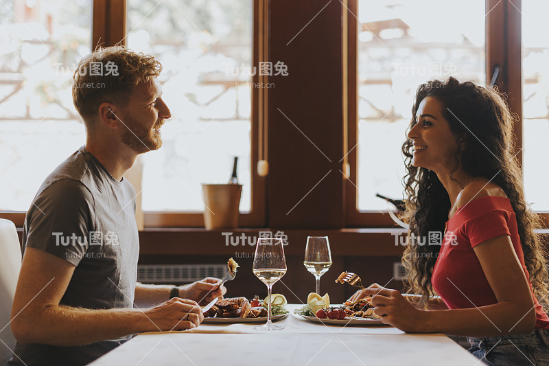 一对年轻夫妇在餐厅喝着白葡萄酒吃午餐