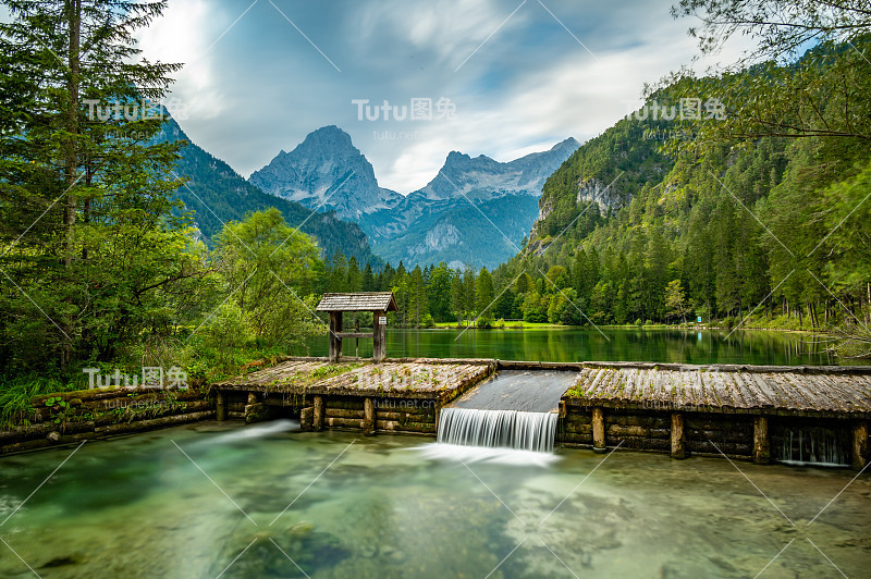 辛特斯托德村附近著名的绿色湖泊Schiederweiher。流水湖上的小堰和坝。背景是巨大的奥地利山脉。纯天然中柔和而神奇的色彩。