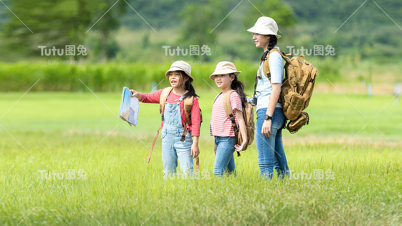 成群的家庭孩子在丛林探险中查看地图。亚洲人旅游的目的地休闲旅行，教育和放松的自然公园。山的背景。