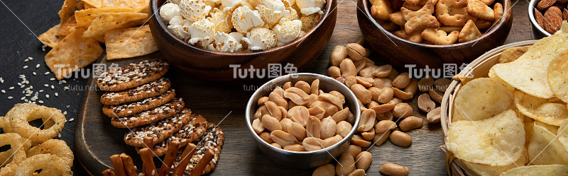 各种咸零食在黑暗的背景。