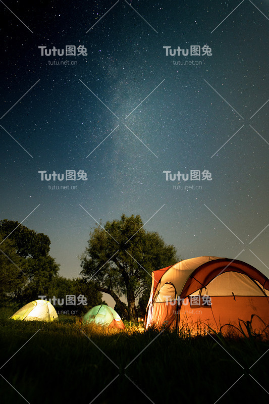 繁星点点的夜晚和绿色田野上的帐篷