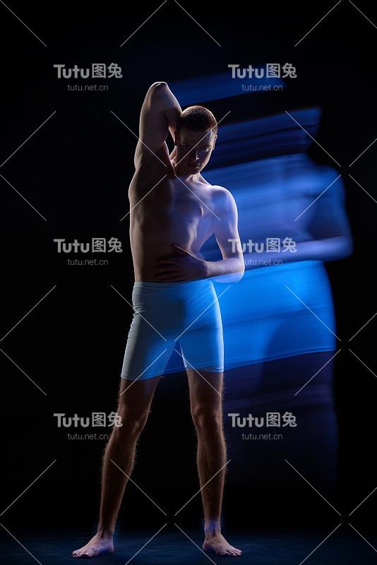 照片年轻迷人的红发男性身体发光霓虹灯在黑暗的背景。混合霓虹灯