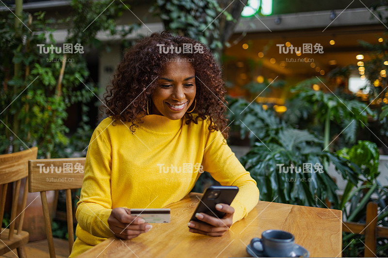 美丽的巴西年轻女子在户外用手机网购