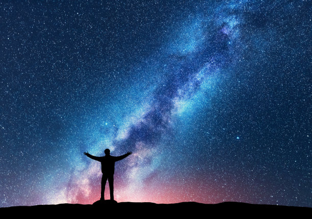 空间。银河的剪影，一个快乐的人举起手臂站在山上。夜景与美丽的银河。宇宙。夜空繁星满天，银河五彩缤纷。星空与人
