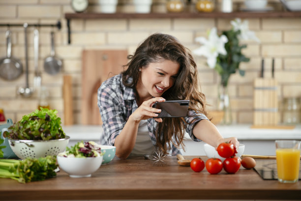 一个年轻女子在厨房里拍摄食物。