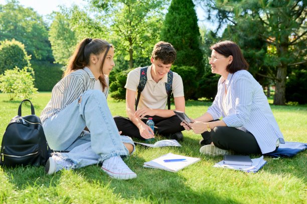 学校老师，心理学家，社会工作者和青少年聊天，坐在草地上