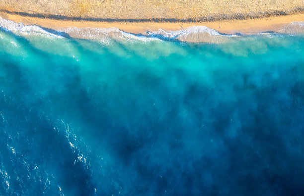 海岸与波浪作为背景从顶视图。蓝水背景从无人机。从空中俯瞰夏日海景。自然景观设计。