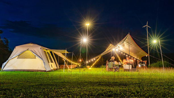 夜间露营的场景，移动部分的长时间曝光是模糊的。
晚上露营帐篷住宿和放松座椅，两个年轻的亚洲青少年在帐篷里吃晚饭。